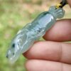 a hand holding a jade pendant