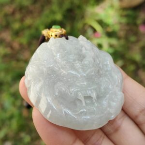 a hand holding a jade pendant