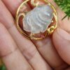a hand holding a gold ring with a white stone in it