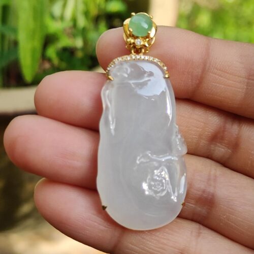 a hand holding a jade pendant