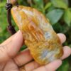 a hand holding a stone pendant