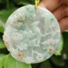 a hand holding a jade pendant