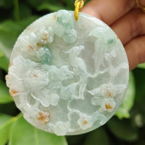 a hand holding a jade pendant
