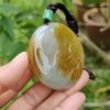 a hand holding a stone pendant
