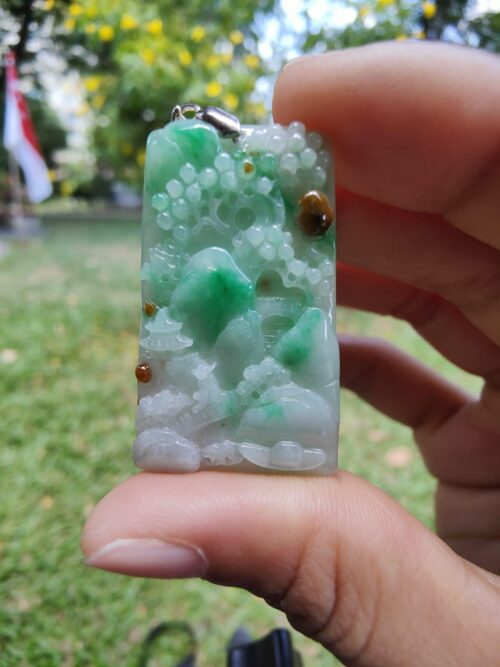 a hand holding a jade pendant