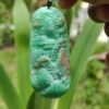 a hand holding a green stone pendant