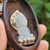 a hand holding a wooden spoon with a carved buddha statue