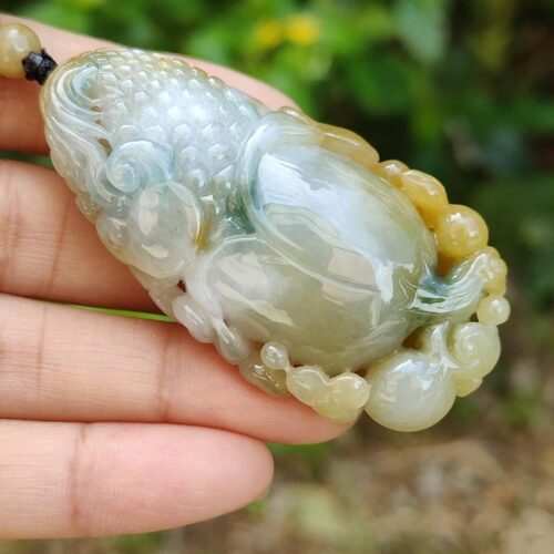 une main tenant un pendentif en jade