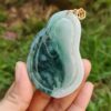 une main tenant un pendentif en jade