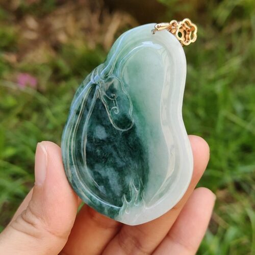 une main tenant un pendentif en jade