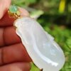 a hand holding a jade pendant