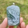 a hand holding a blue pendant