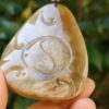 a hand holding a stone pendant