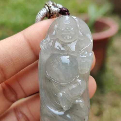 une main tenant un pendentif en jade