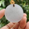 a hand holding a white circle pendant