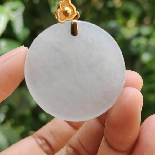 a hand holding a white circle pendant