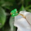 a finger with a ring with green stones