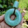 a hand holding a jade pendant