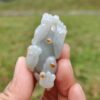 a hand holding a small white and orange stone