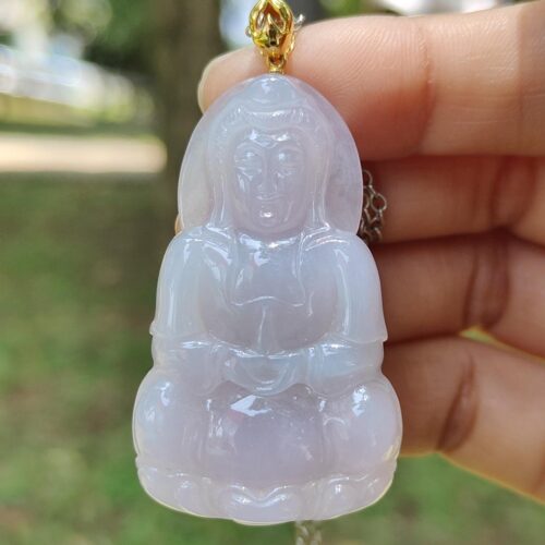 a hand holding a jade pendant