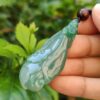 Una mano sosteniendo un colgante de jade.