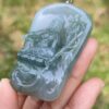 a hand holding a jade pendant