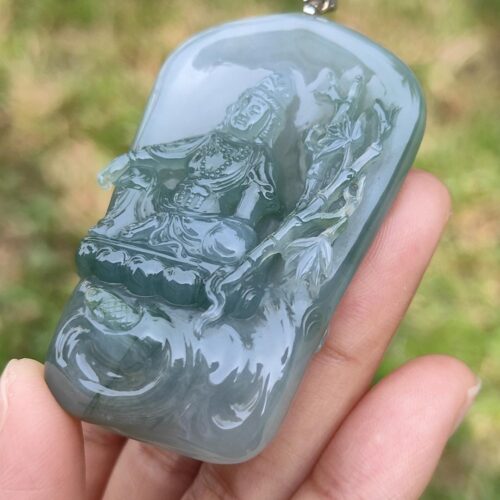 a hand holding a jade pendant