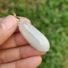 Una mano sosteniendo un colgante de jade blanco.