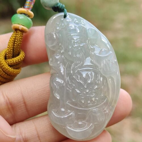 a hand holding a jade pendant