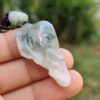 a hand holding a jade elephant head necklace