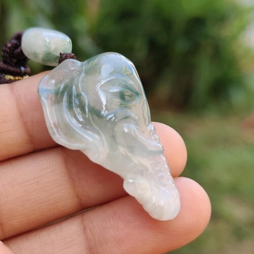 a hand holding a jade elephant head necklace