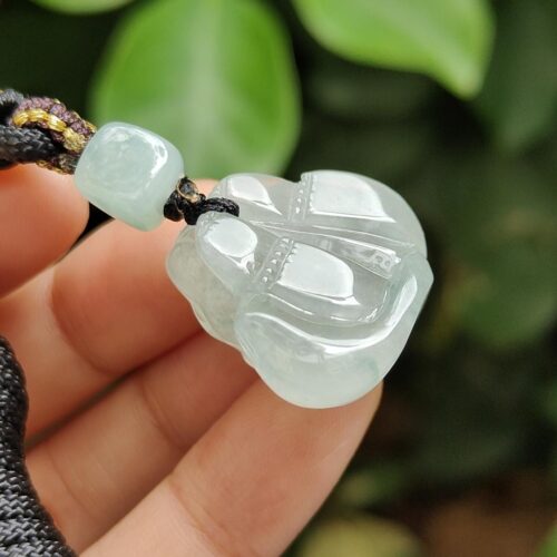 a hand holding a jade pendant