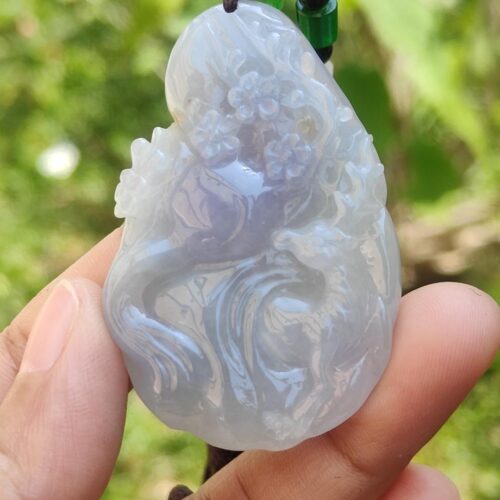 a hand holding a jade pendant
