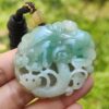 a hand holding a jade pendant