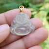 a hand holding a clear buddha pendant