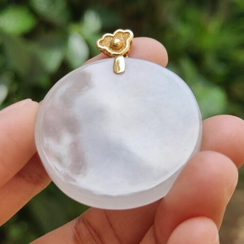 a hand holding a round white object with a gold flower on top