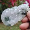 a hand holding a white and green carved object
