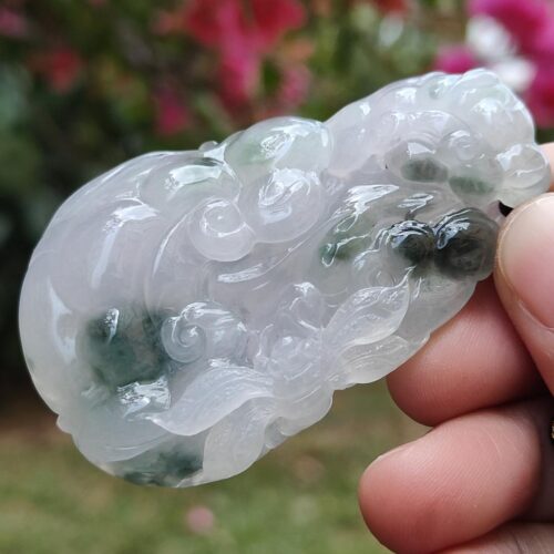 a hand holding a white and green carved object