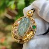 a hand in a glove holding a gold pendant