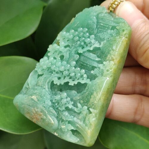 a hand holding a jade pendant