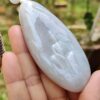 Una mano sosteniendo un colgante de jade blanco.