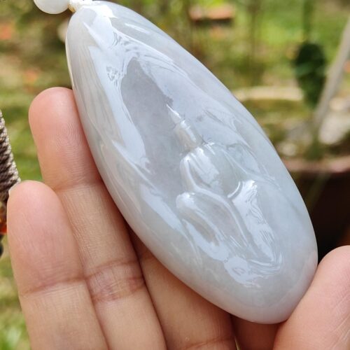Una mano sosteniendo un colgante de jade blanco.