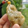 a hand holding a jade pendant