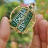 a hand holding a green and gold pendant