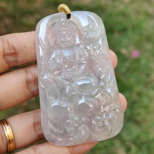 a hand holding a jade pendant