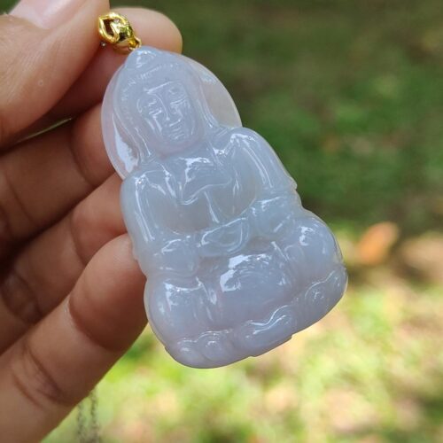 a hand holding a jade pendant