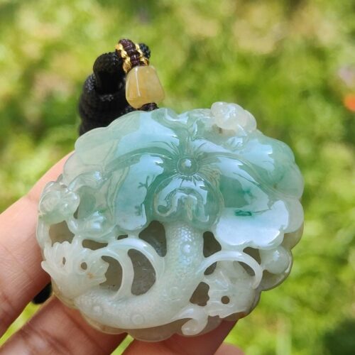a hand holding a jade pendant