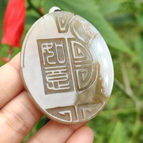 a hand holding a stone with a design on it