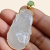 a hand holding a jade pendant