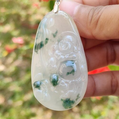 a hand holding a white and green pendant